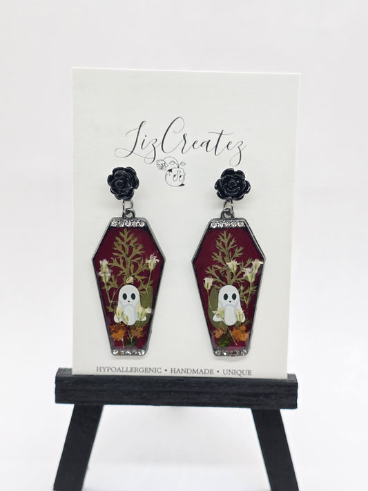Coffin-shaped earrings with pressed flowers, a ghost design, black rose studs, and rhinestone trim, displayed on a LizCreatez card