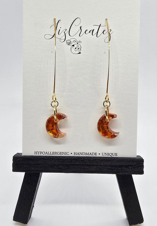 Mini moon-shaped earrings filled with orange glitter resin on gold v-hooks