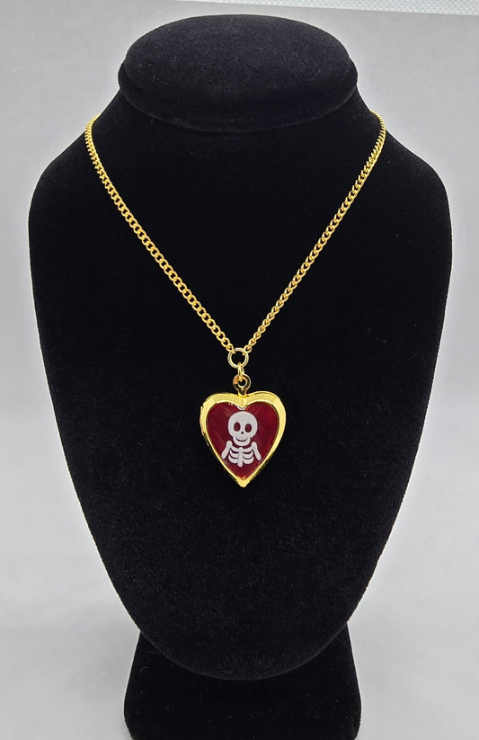 Gold heart locket necklace with a skeleton design on red enamel, on an 18-inch gold chain