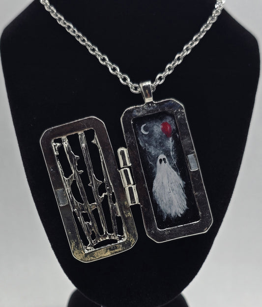 Silver door-shaped locket necklace with a hand-painted ghost under a moon and red balloon, glow-in-the-dark details, on an 18-inch chain